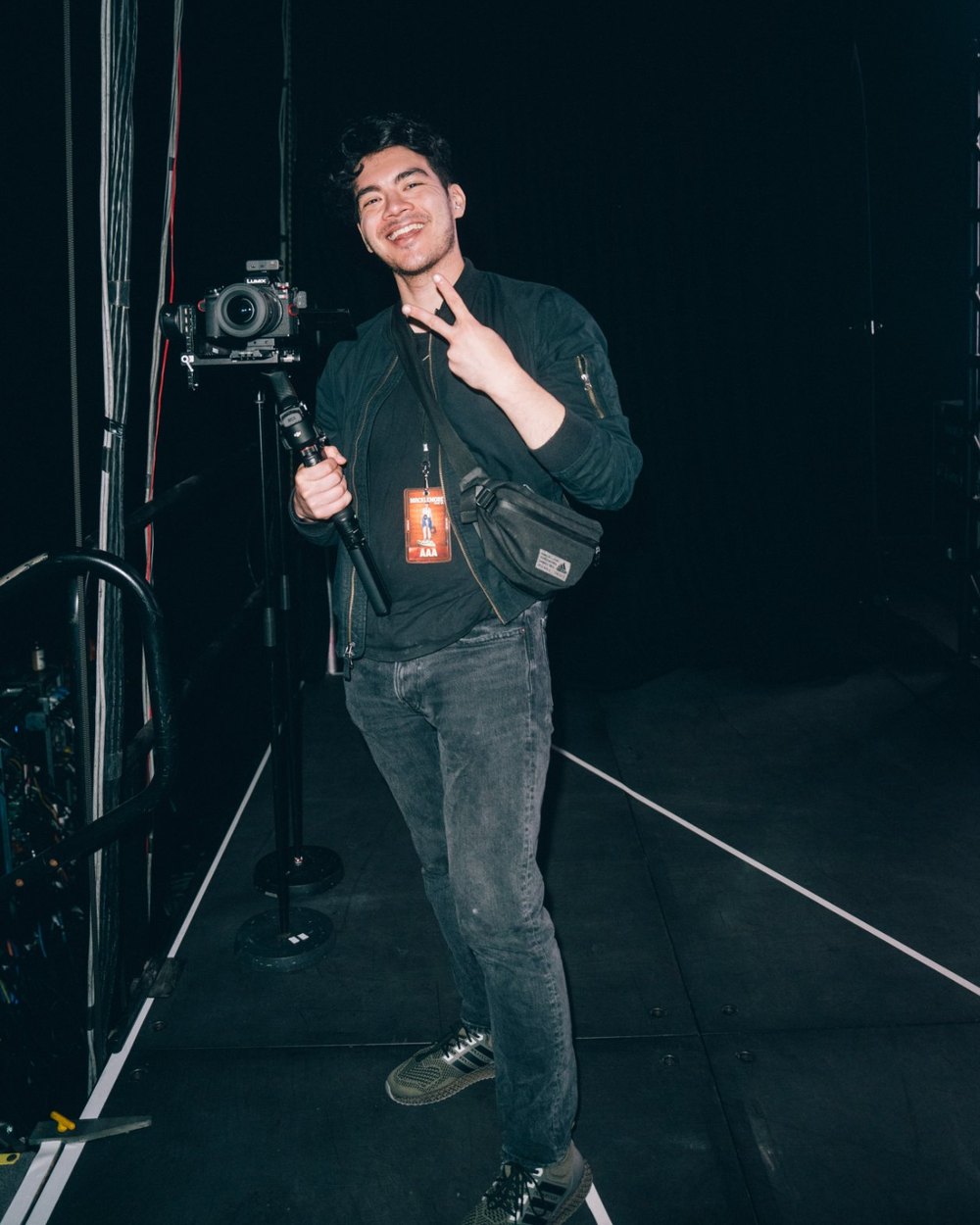 Charles backstage on the BEN Tour, holding a camera on a gimbal and throwing a peace sign