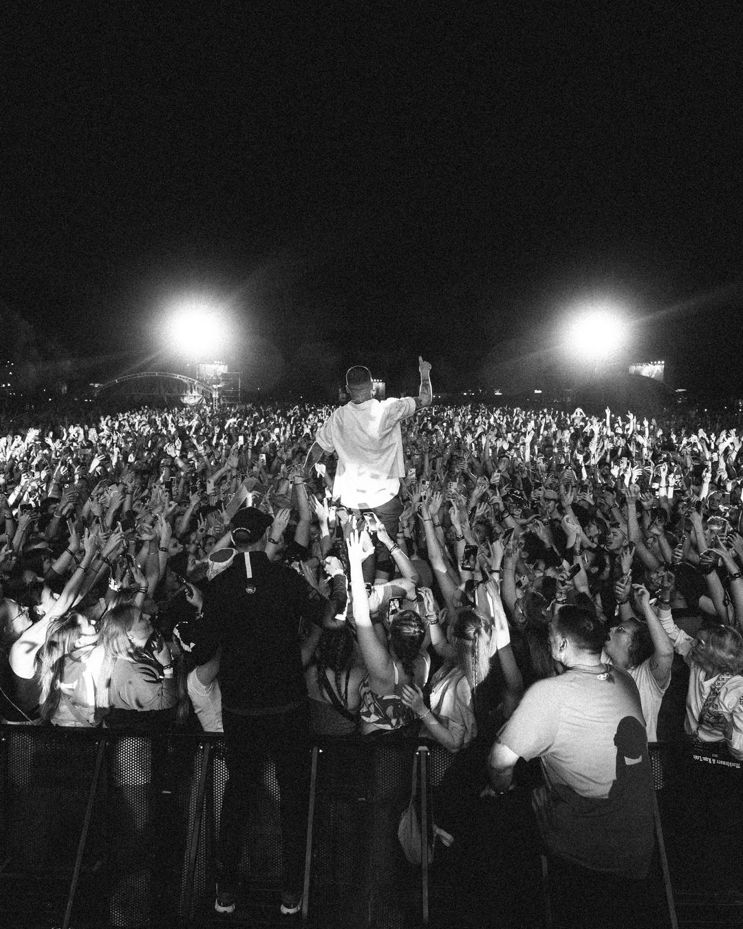 Macklemore held up over a packed festival crowd, arms reaching toward him